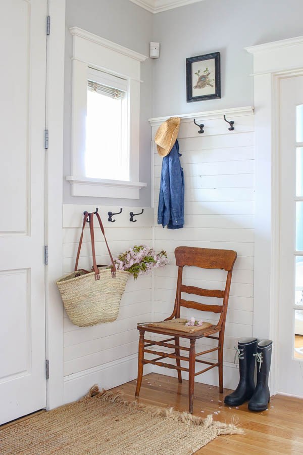 A small entryway with coat hooks and a small chair.