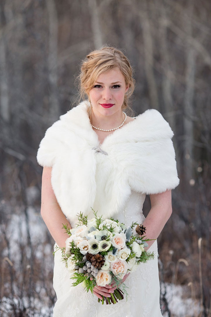 A bride in a white fur stole holding a bouquet.