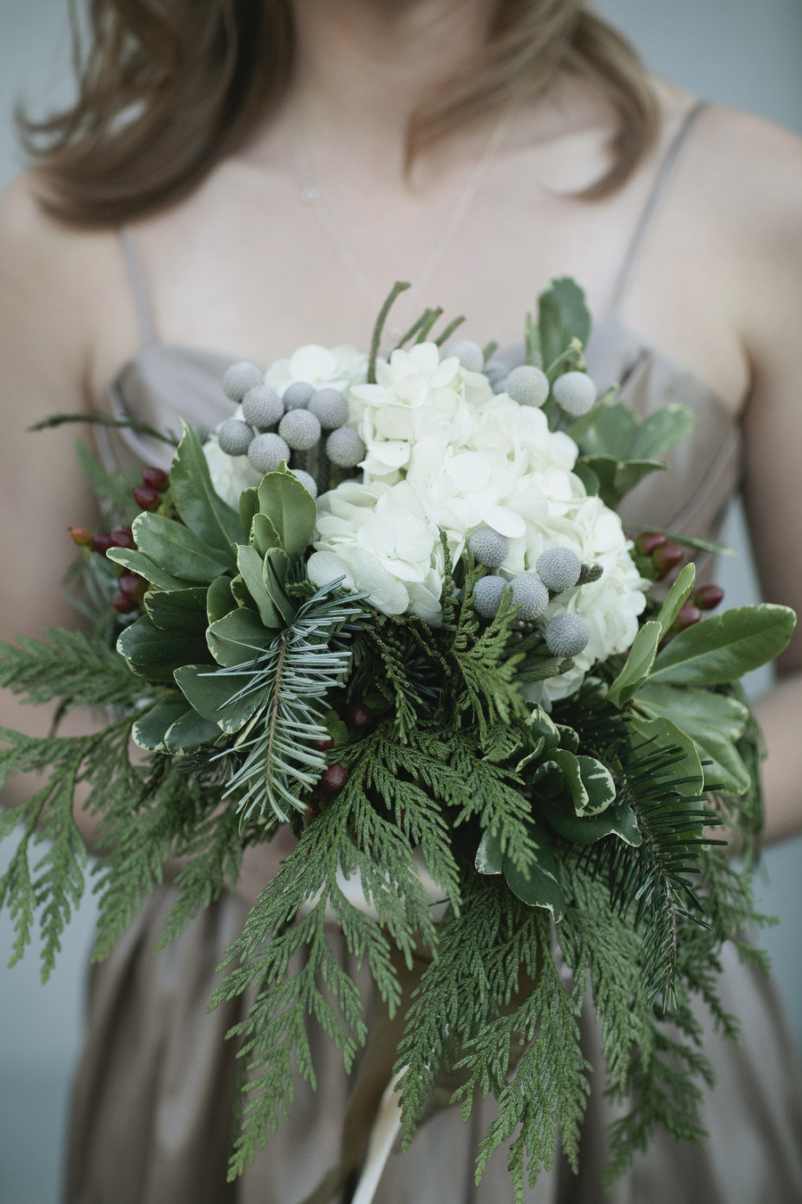 Evergreen and white flowers in a bouquet.