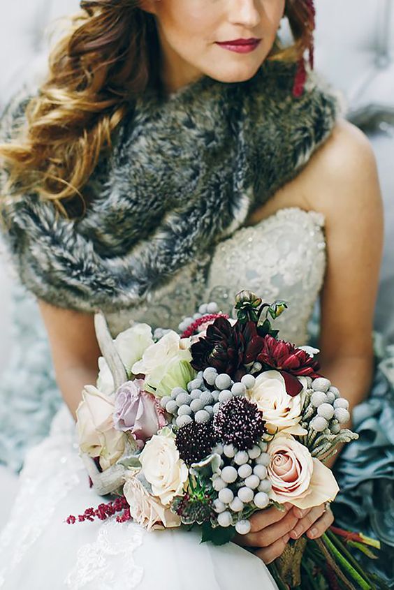 A grey fur stole on a bride with multi coloured winter bouquet.