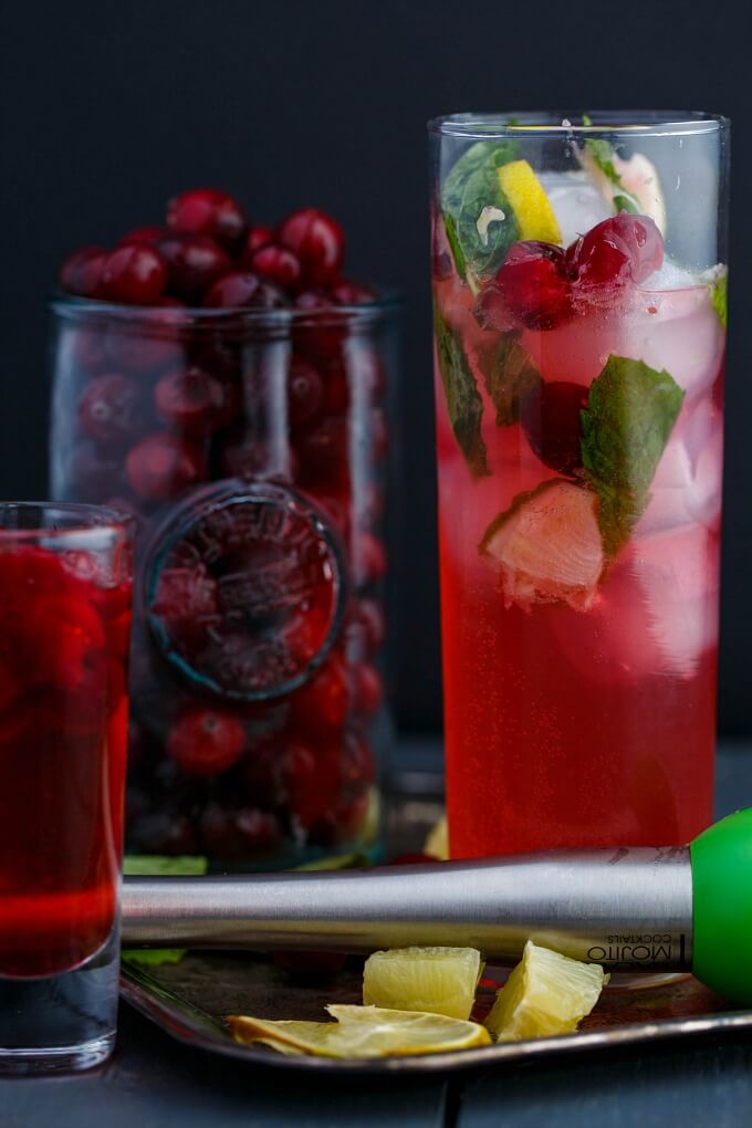Cranberry mojitos in tall glasses with a glass filled with cranberries.