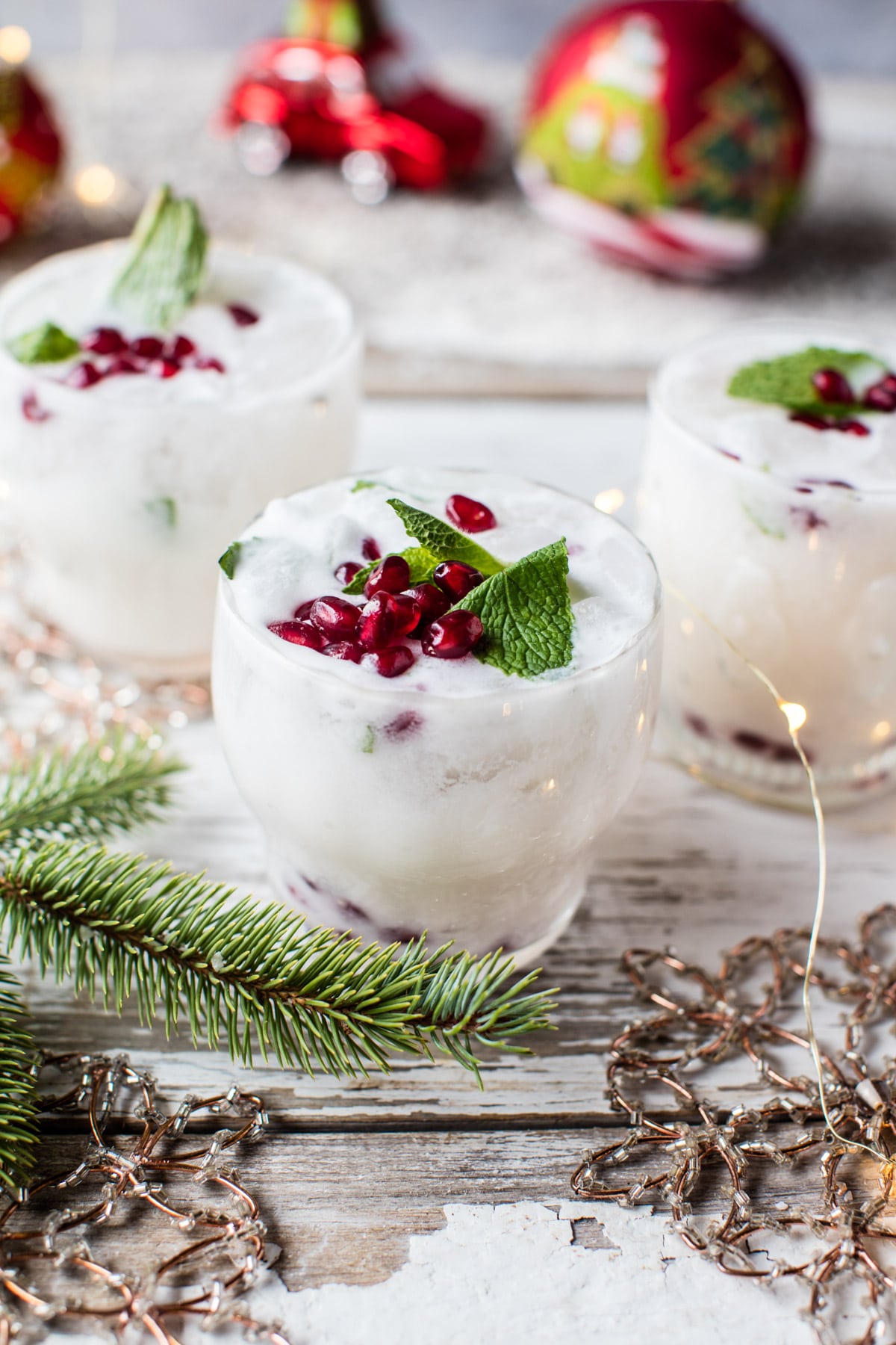 A white mojito with pomegranate seeds on top and sprigs of mint.