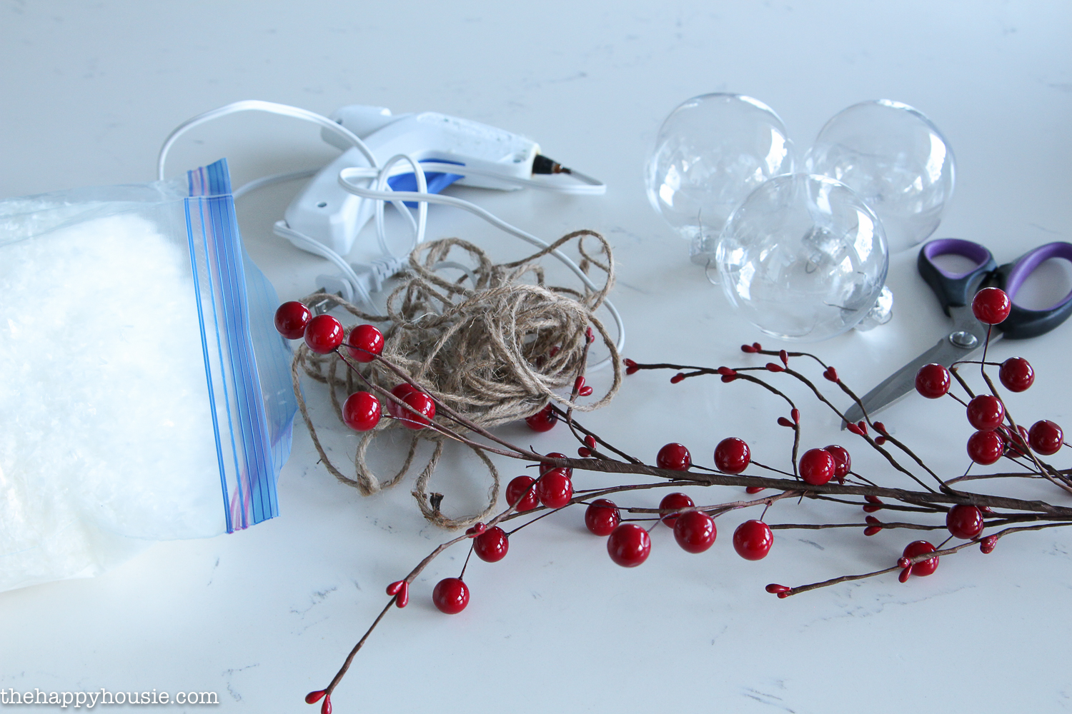 A branch of red berries, scissors and twine on the table.