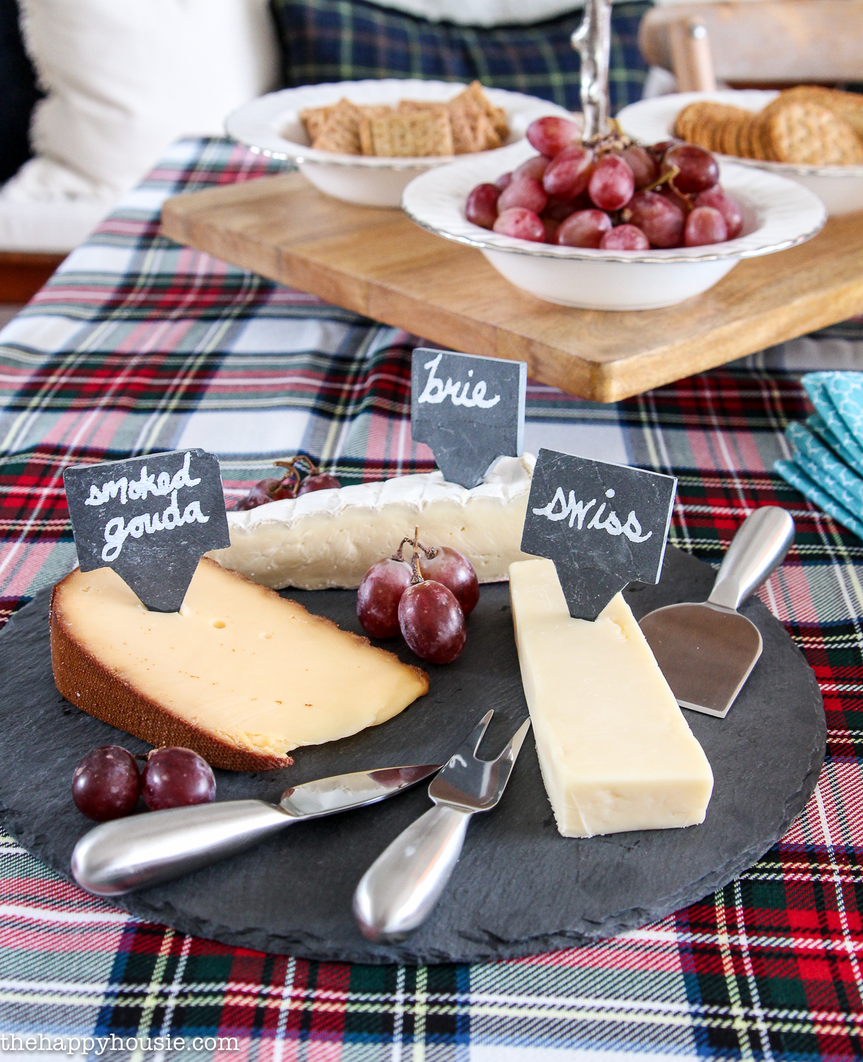 A cheese plate with signs stating what the cheeses are on a plate.