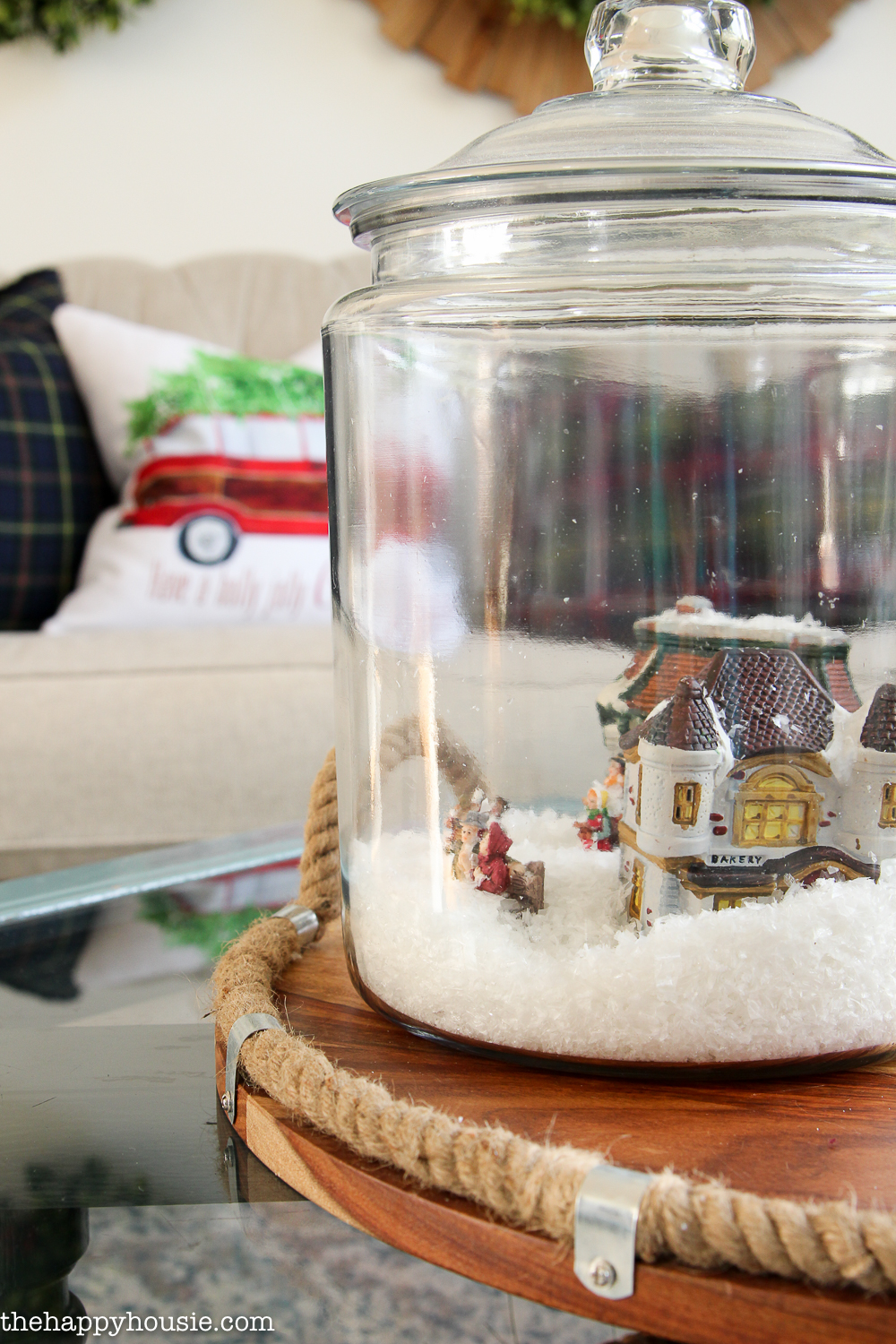 There is a glass jar with a holiday village inside it.