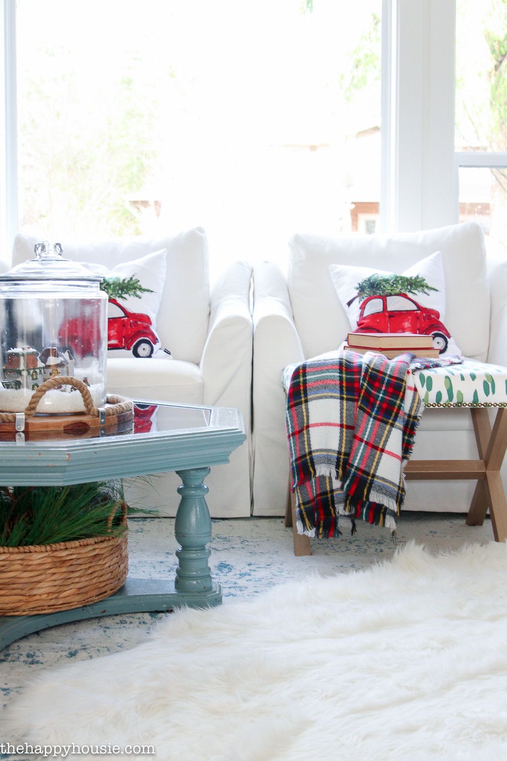 Christmas throw pillows are on the white armchairs.