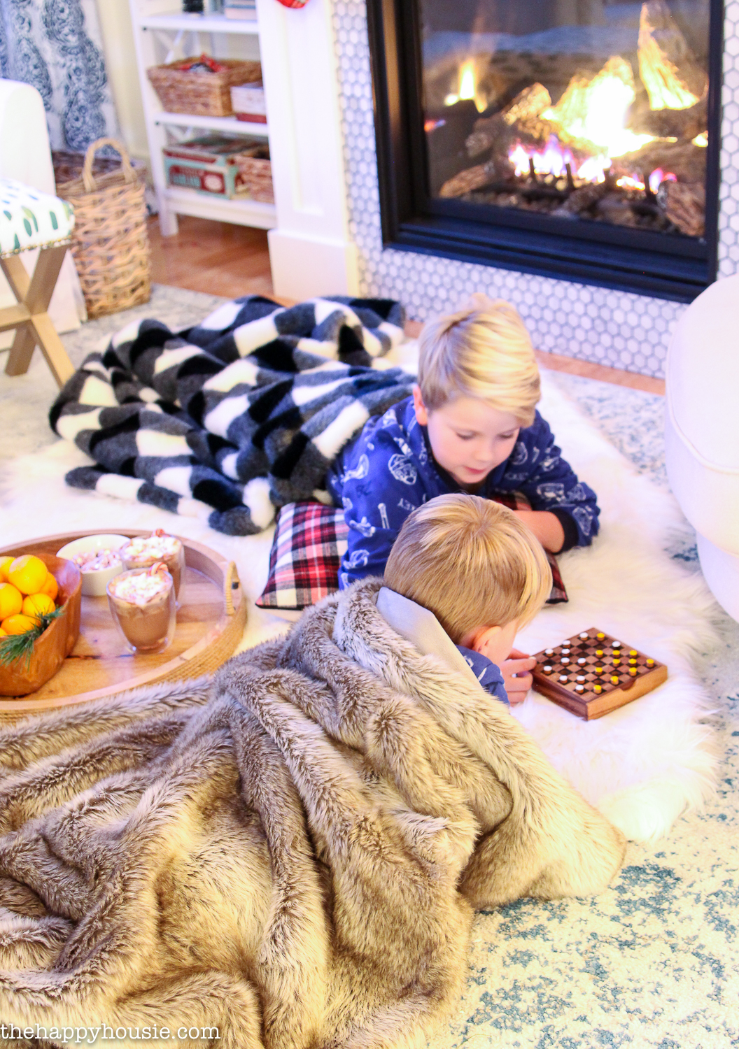 Two boys playing games in front of the fireplace.