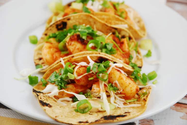Chipolte shrimp tacos on a white plate.