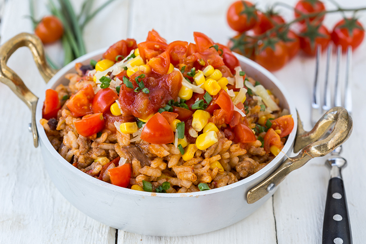 Rice, beans, tomatoes and corn in a dish on the table.