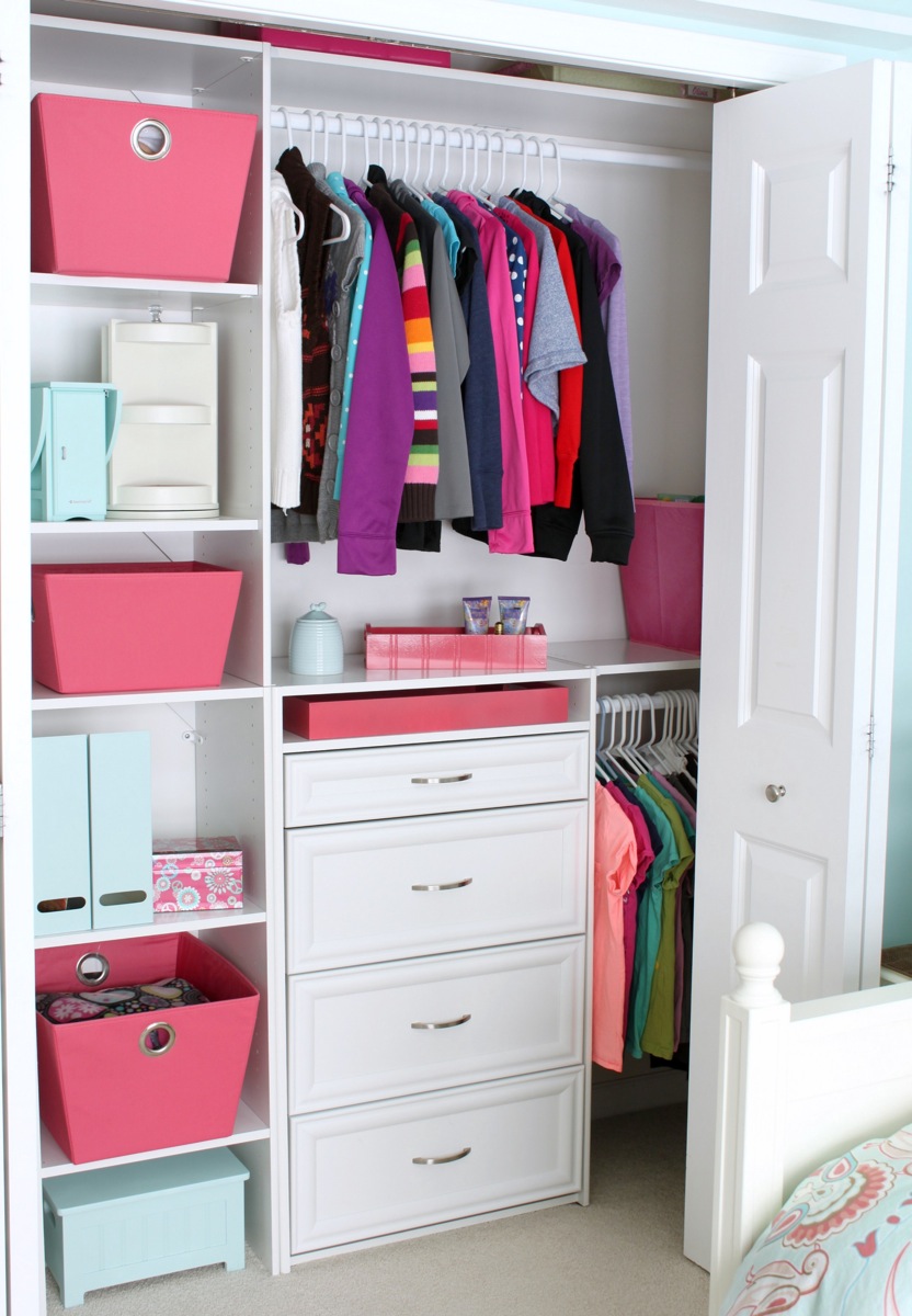 An organized closet with pops of pink baskets.
