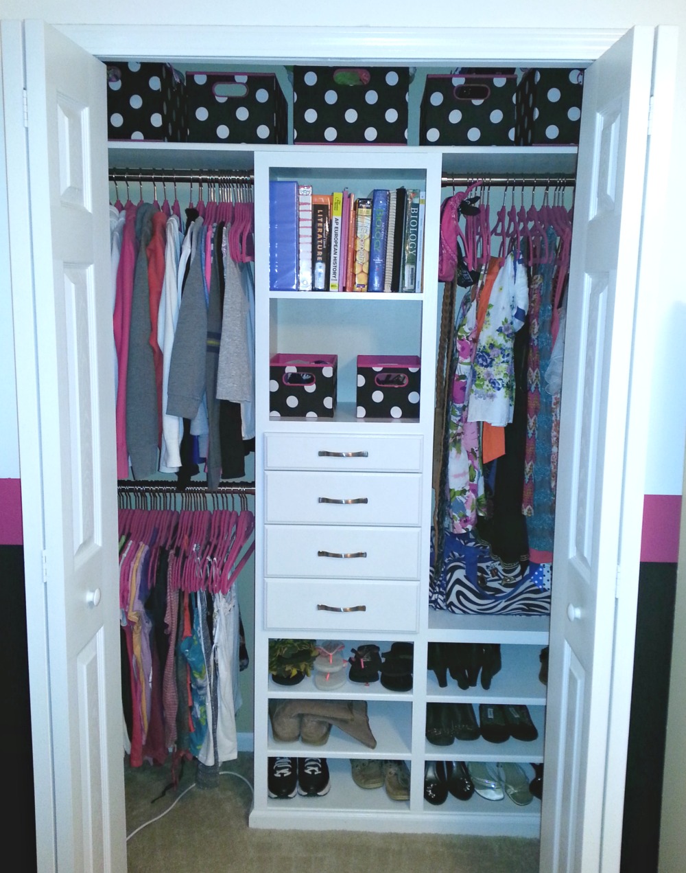 Pink hangers are in this small closet.