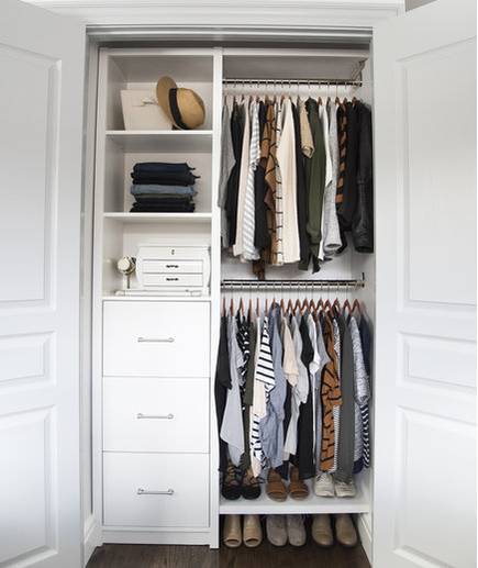 A small closet with drawers and shelving on one side and the other side are clothes hanging up.