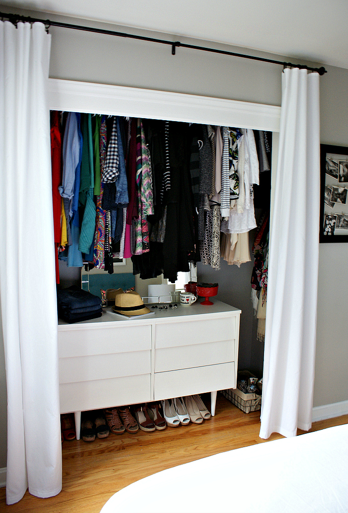 A small white dresser is in the closet with shoes underneath.