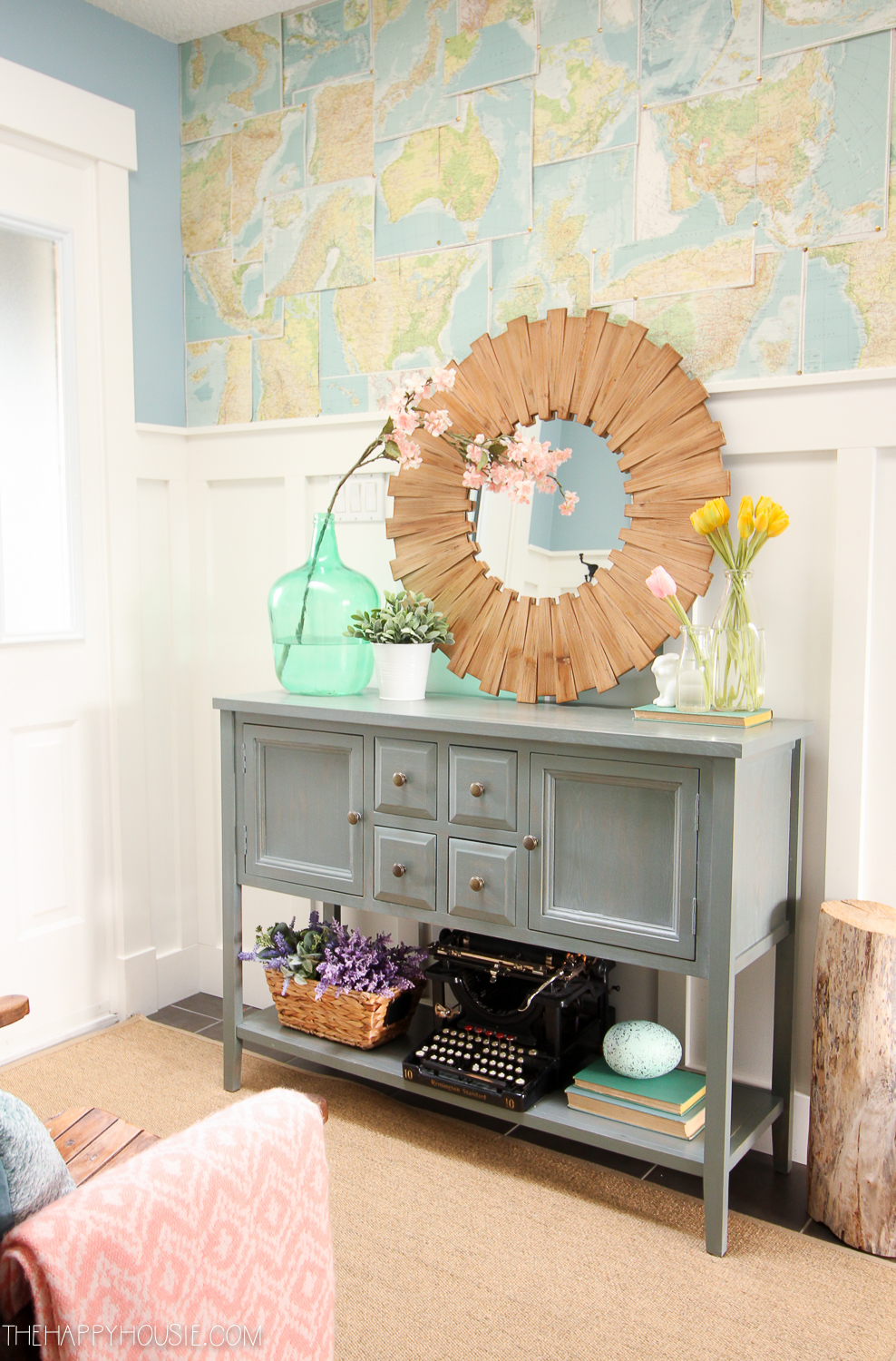 A wooden sunburst mirror with a map above it in the entryway.