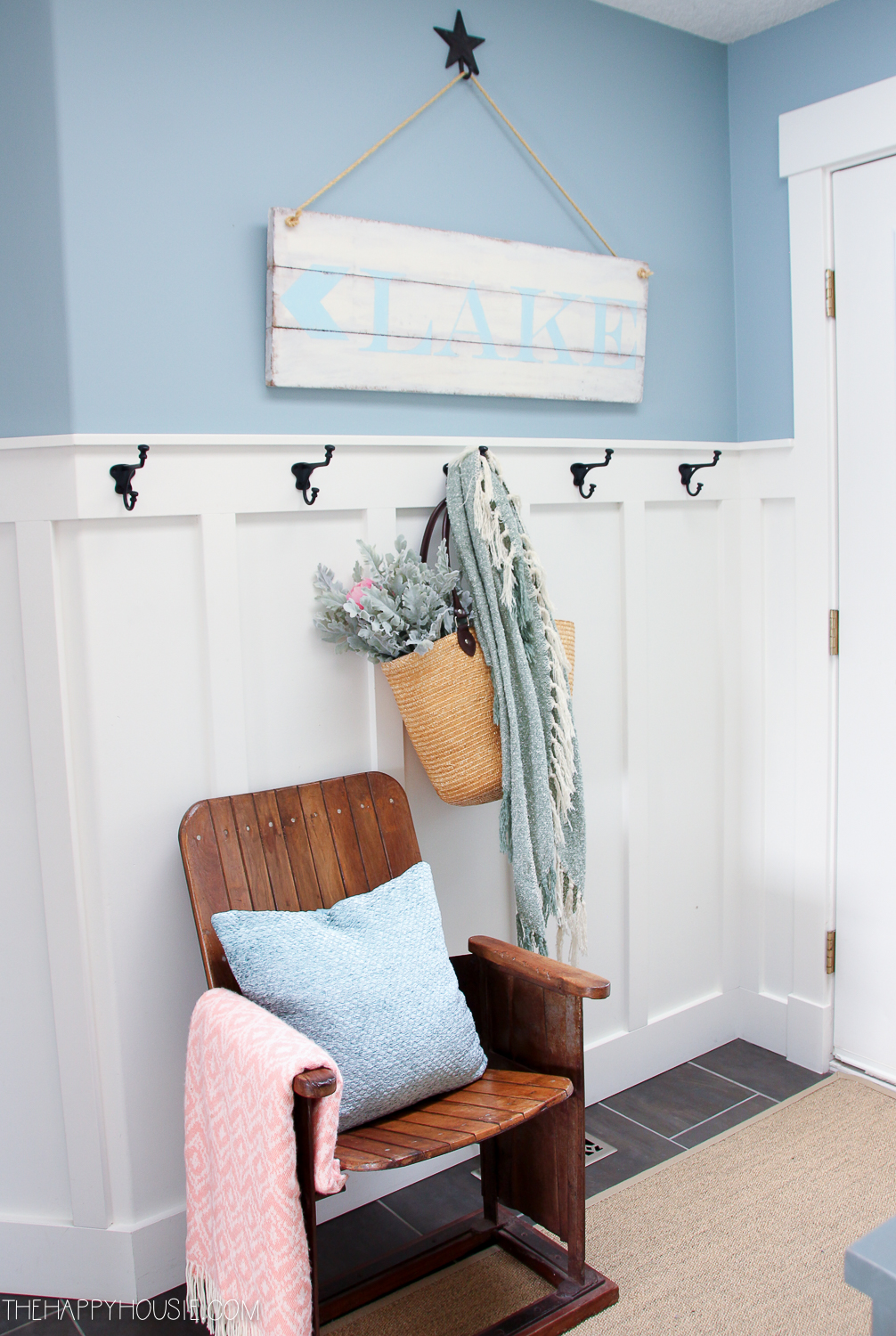 Small black hooks on the wall with a basket and a throw blanket on it.
