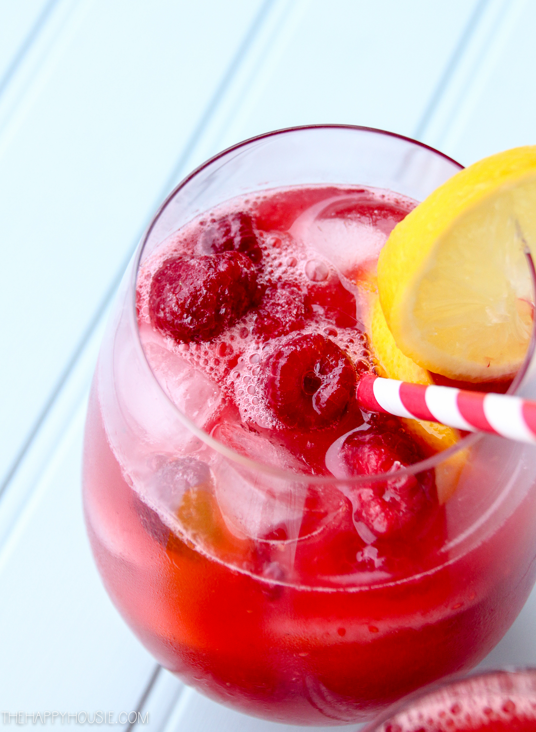 Raspberries in the sangria with a straw.