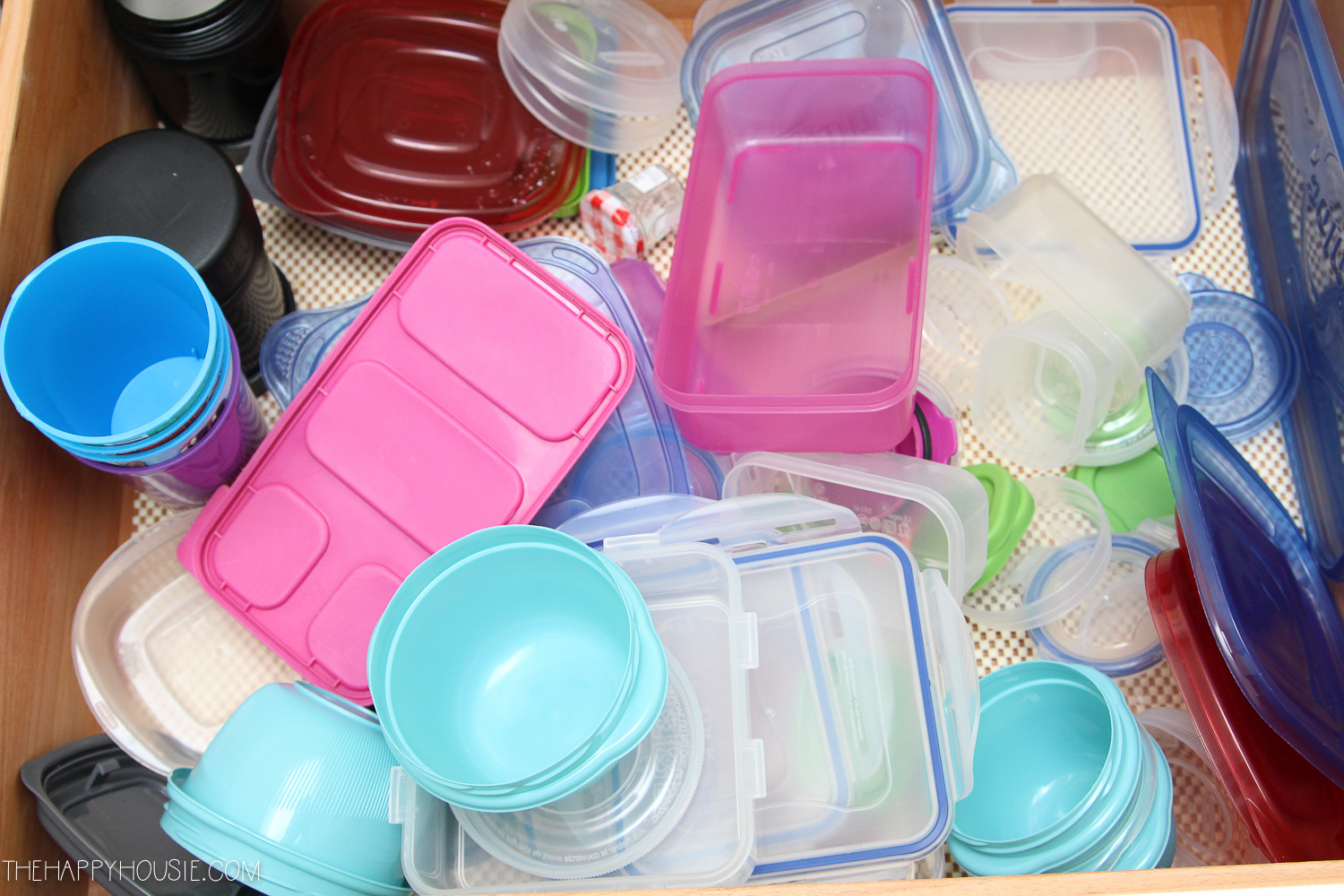 Taking all of the plastic containers out of the cupboard.