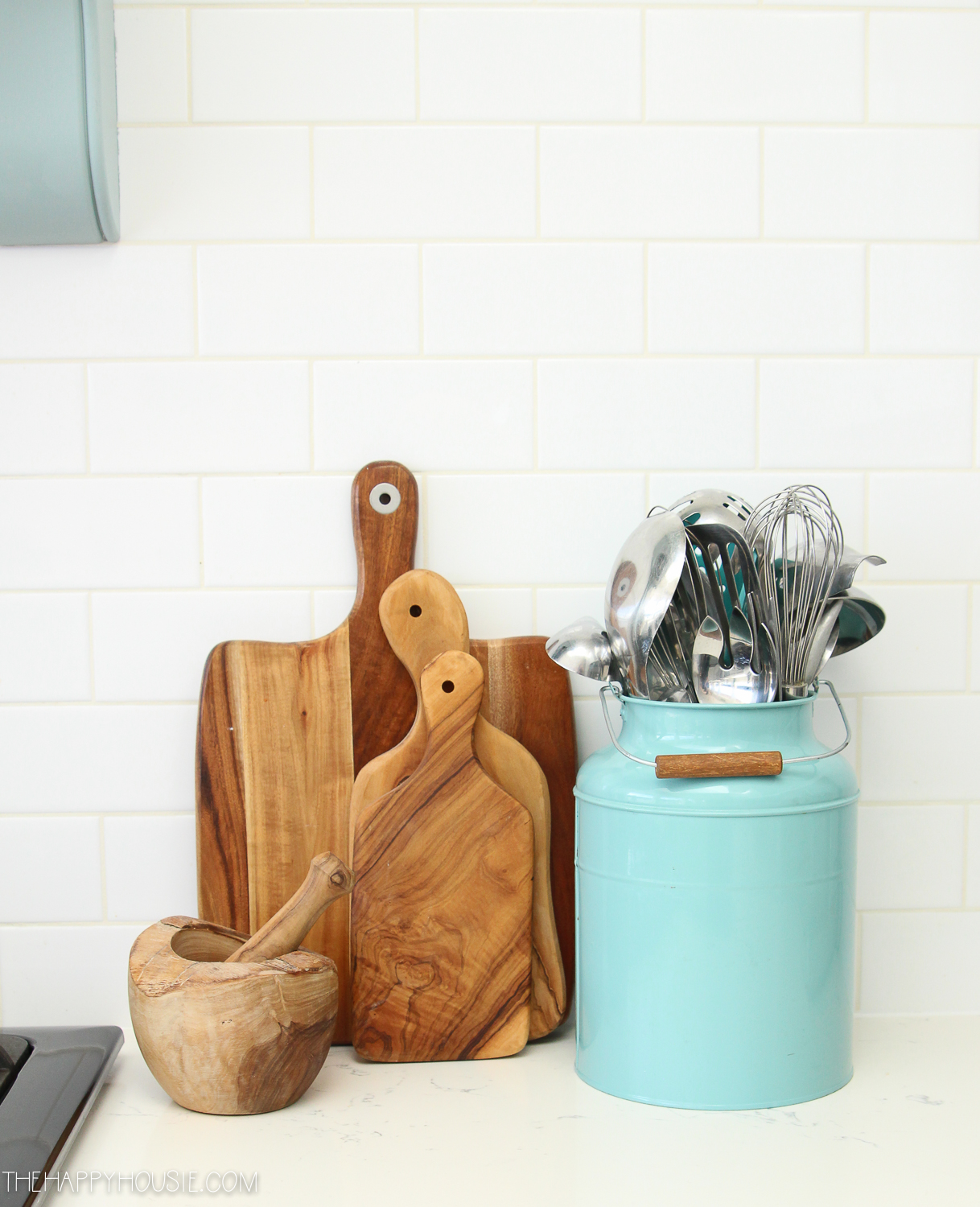 A blue canister filled with kitchen utensils and wooden cutting boards beside it.