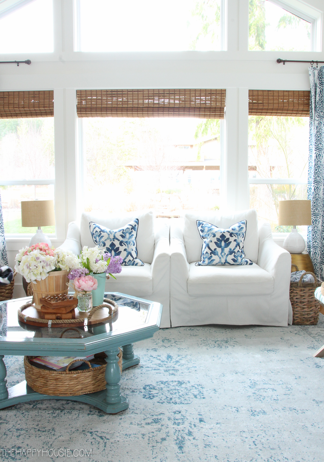 There are two white armchairs with blue pillows in the living room.