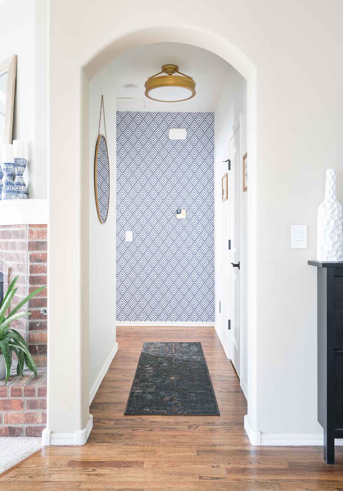 A small hallway with wallpaper in blue and white at the end.