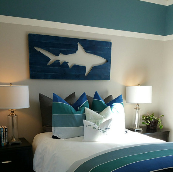 A blue, white and green room with a cut out picture of a shark over the bed.