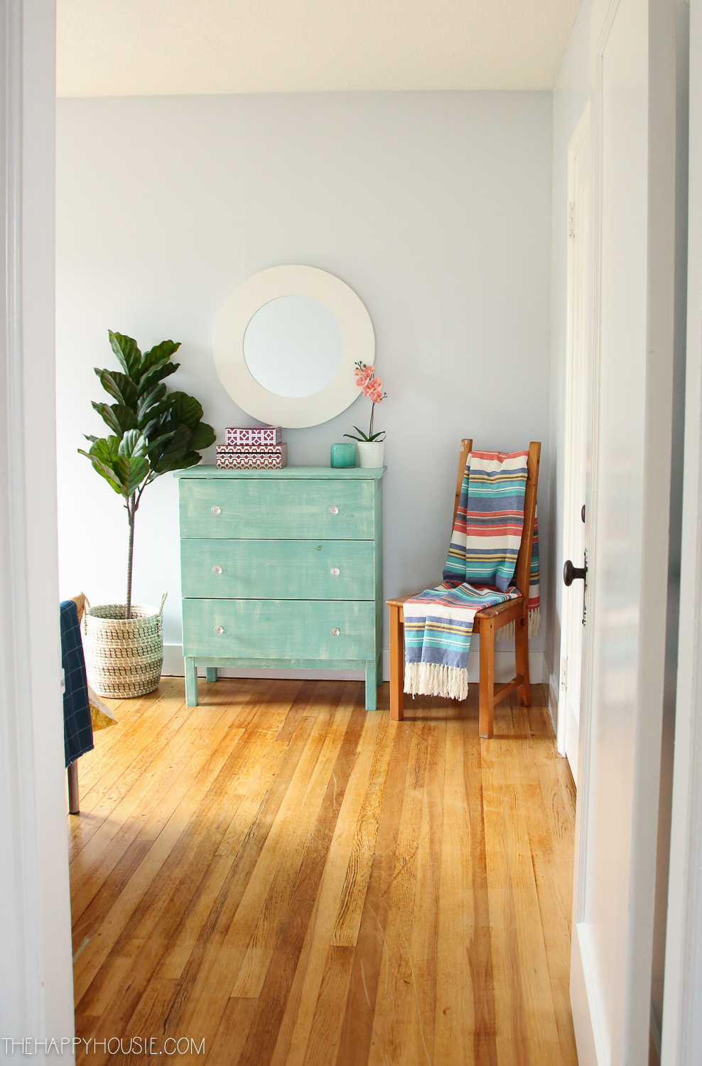 Wood floors and a turquoise dresser.