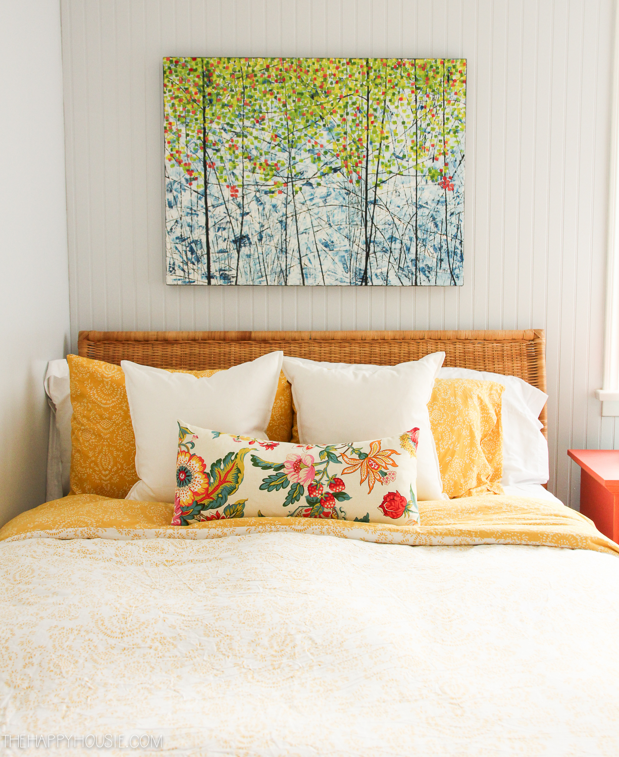 There are throw pillows on the bed in floral and light yellow.