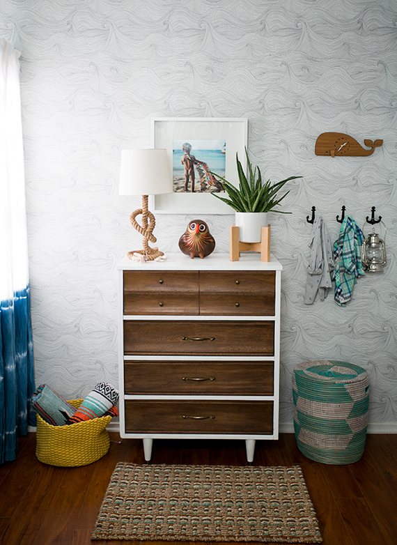 A white and wood dresser with an owl on top and a rope nautical lamp.