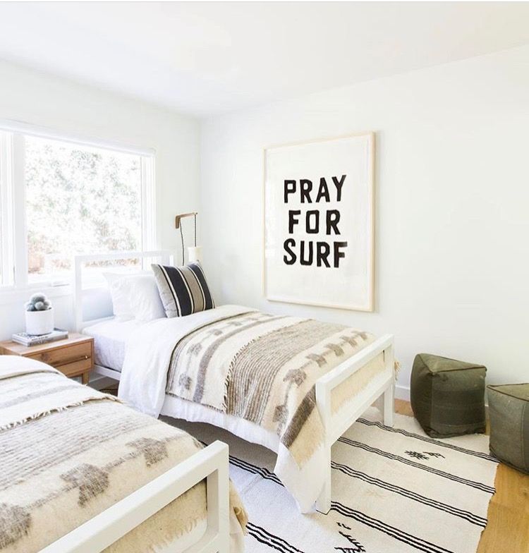 A picture that says pray for surf is on the wall with two single beds in the room.