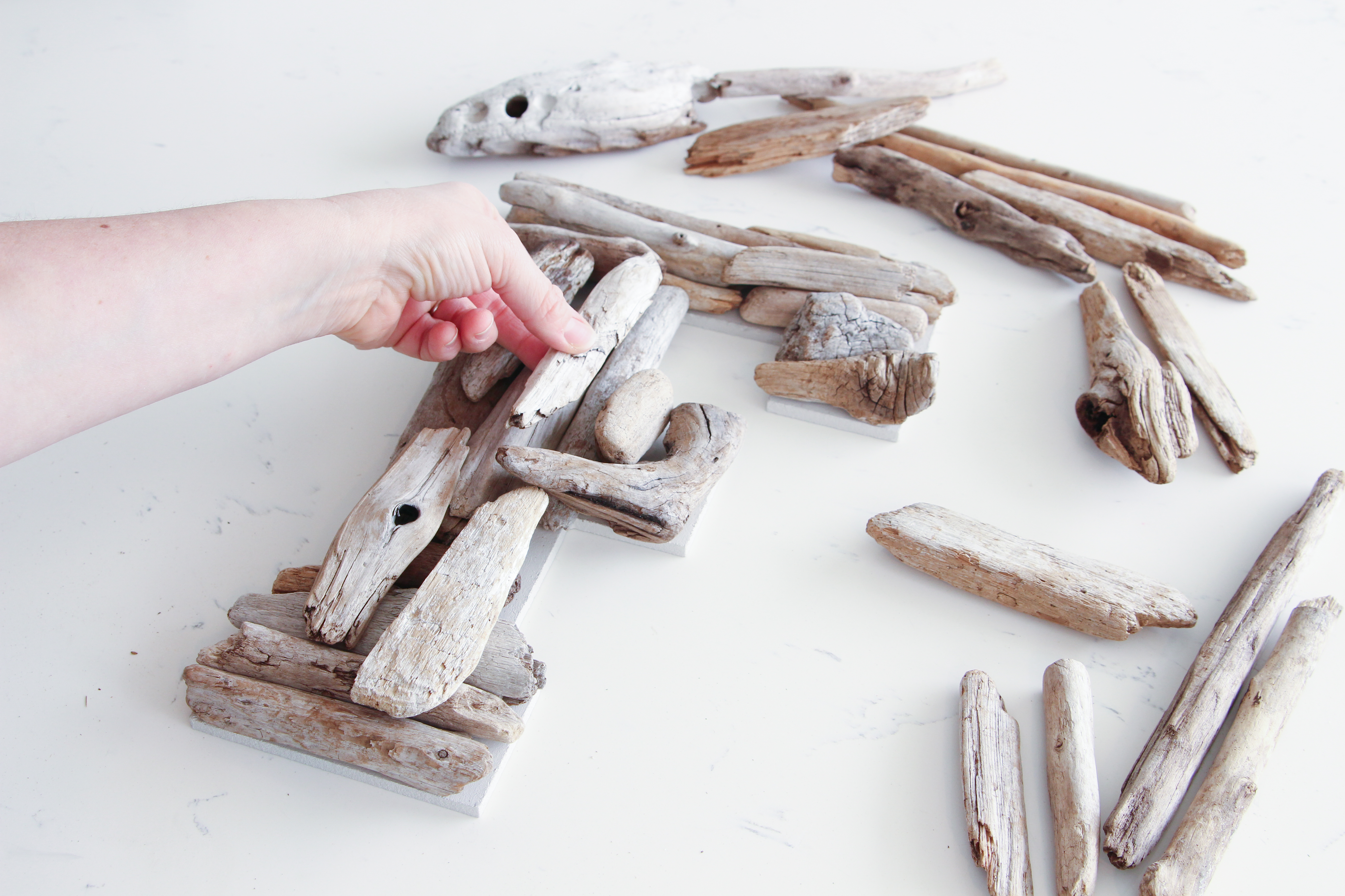 Arranging the pieces of driftwood onto the wooden letter.