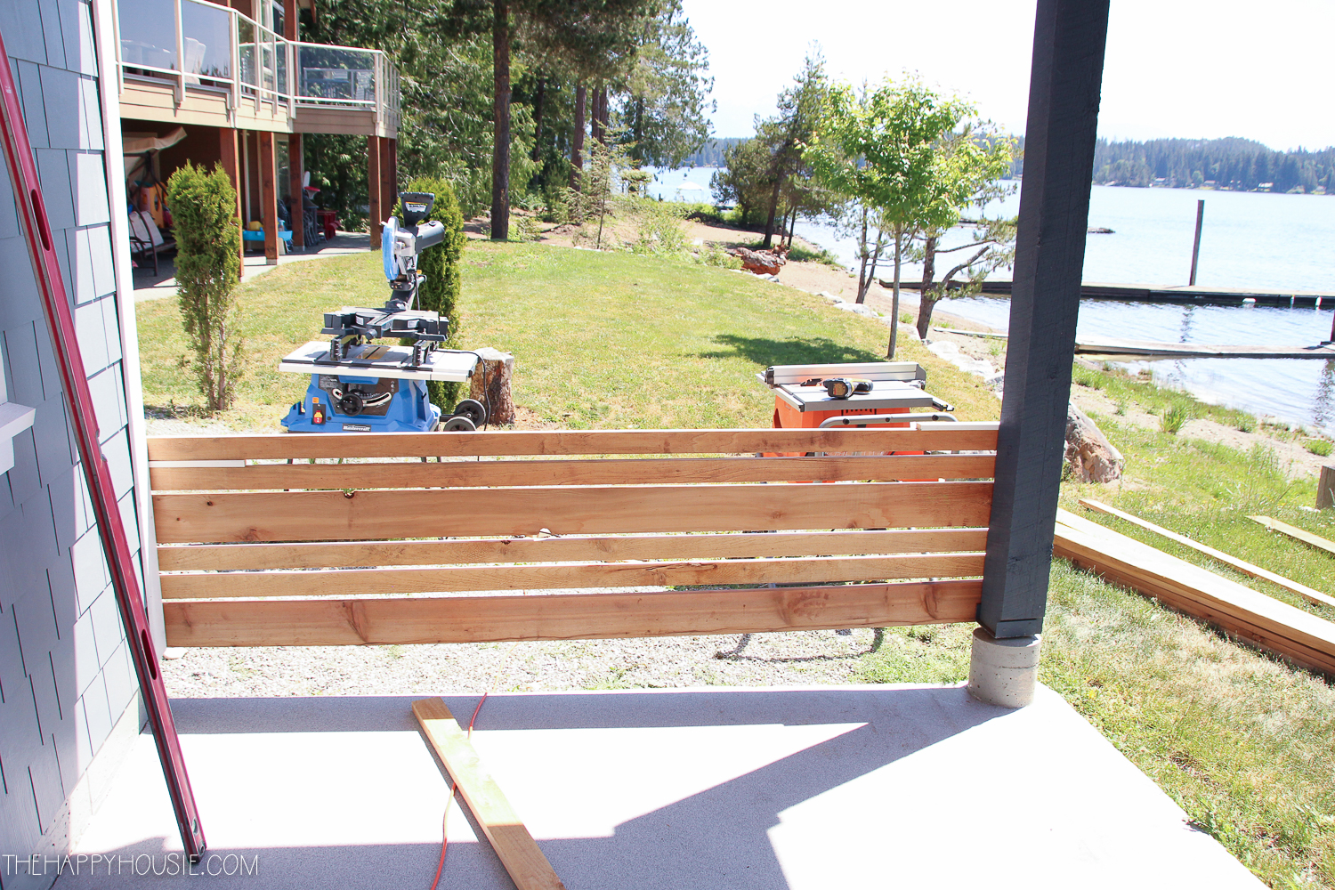 The wood being nailed into place on the porch beside the saw.