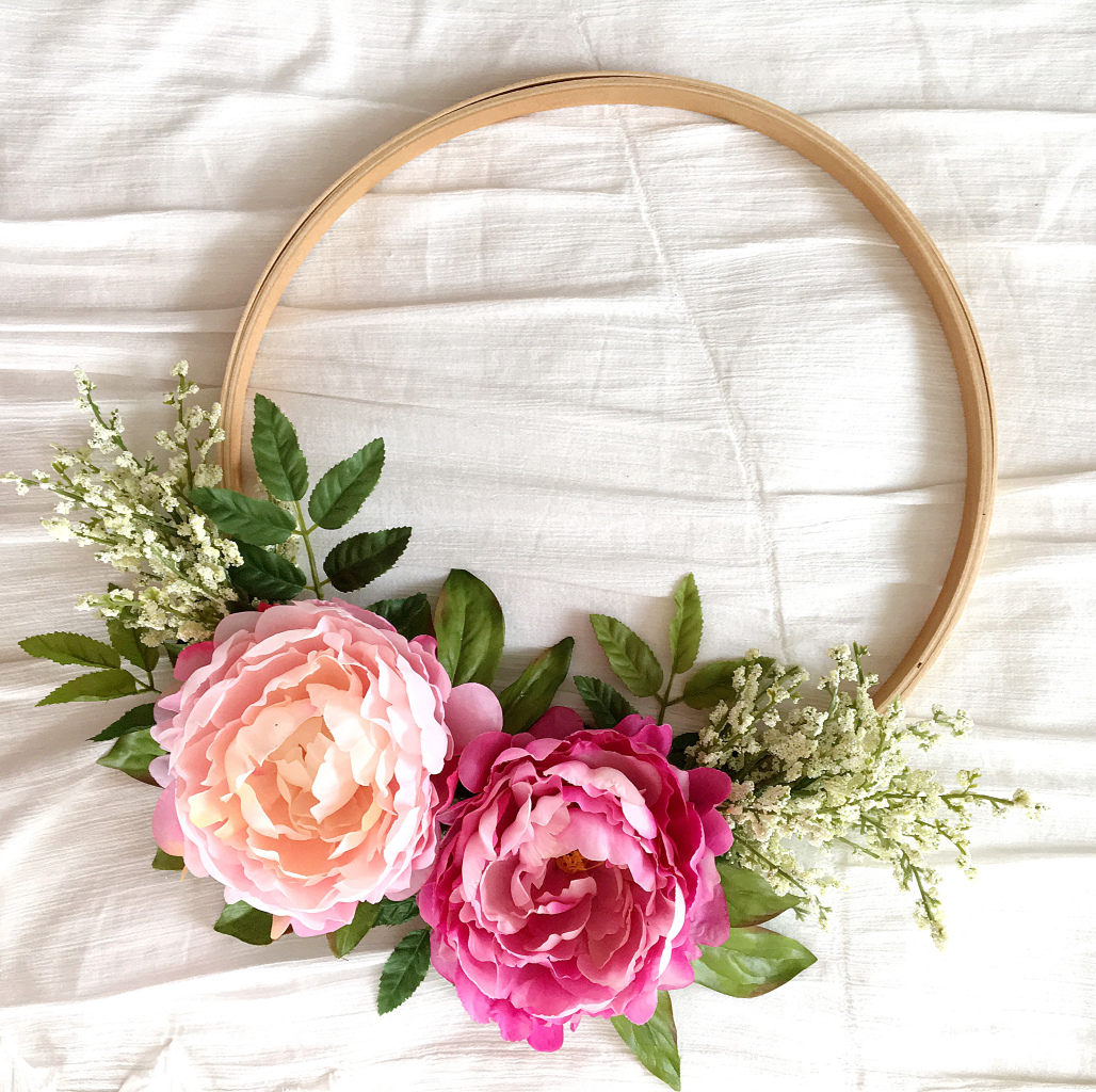 An embroidery hoop with white and pink flowers on it.