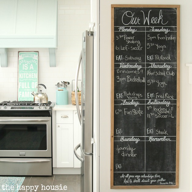 A chalkboard on the wall beside the kitchen.
