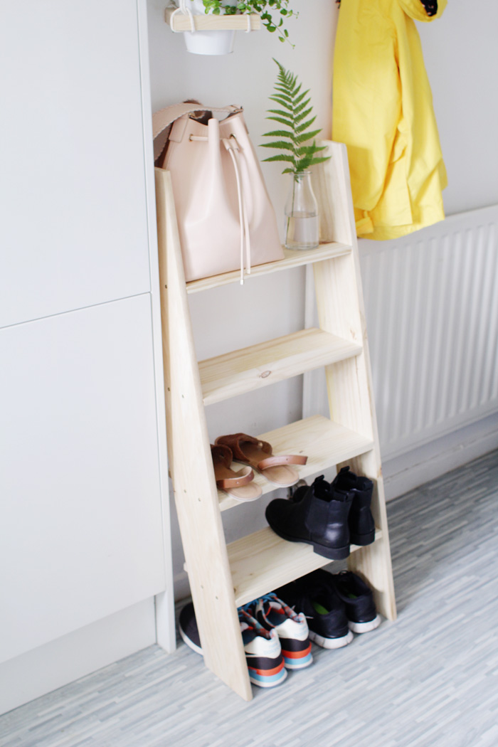 A wooden faux ladder shoe storage leaning against the wall.