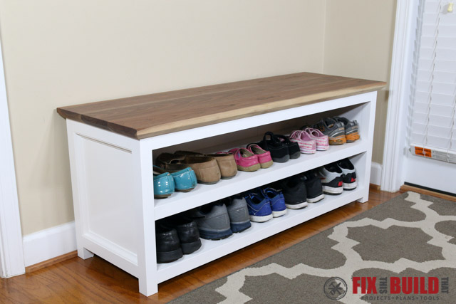 A white with a wooden top bench with shoe storage underneath.