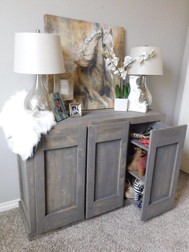 A distressed gray cabinet with doors that open revealing storage.