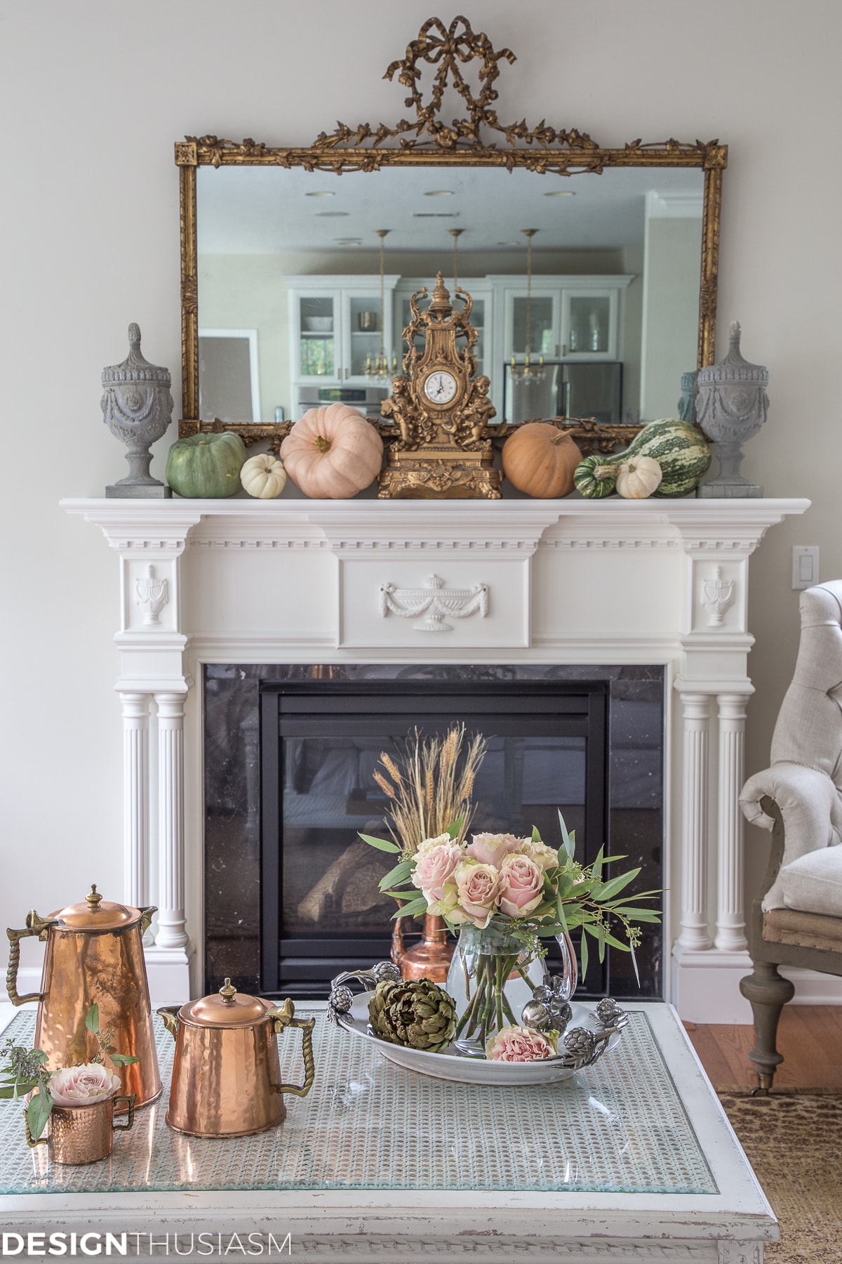White fireplace with pumpkins on the mantel and an ornate mirror above it.