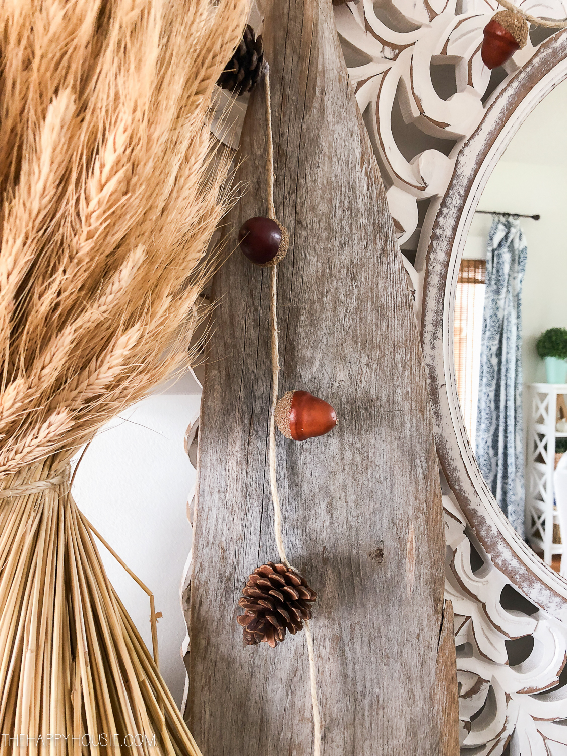 The acorn and pinecone garland strung up around the mirror in a fall vignette.