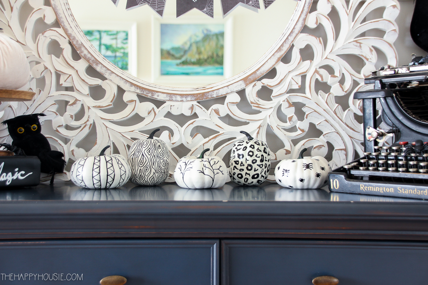 White pumpkins with black decorations using a sharpie.