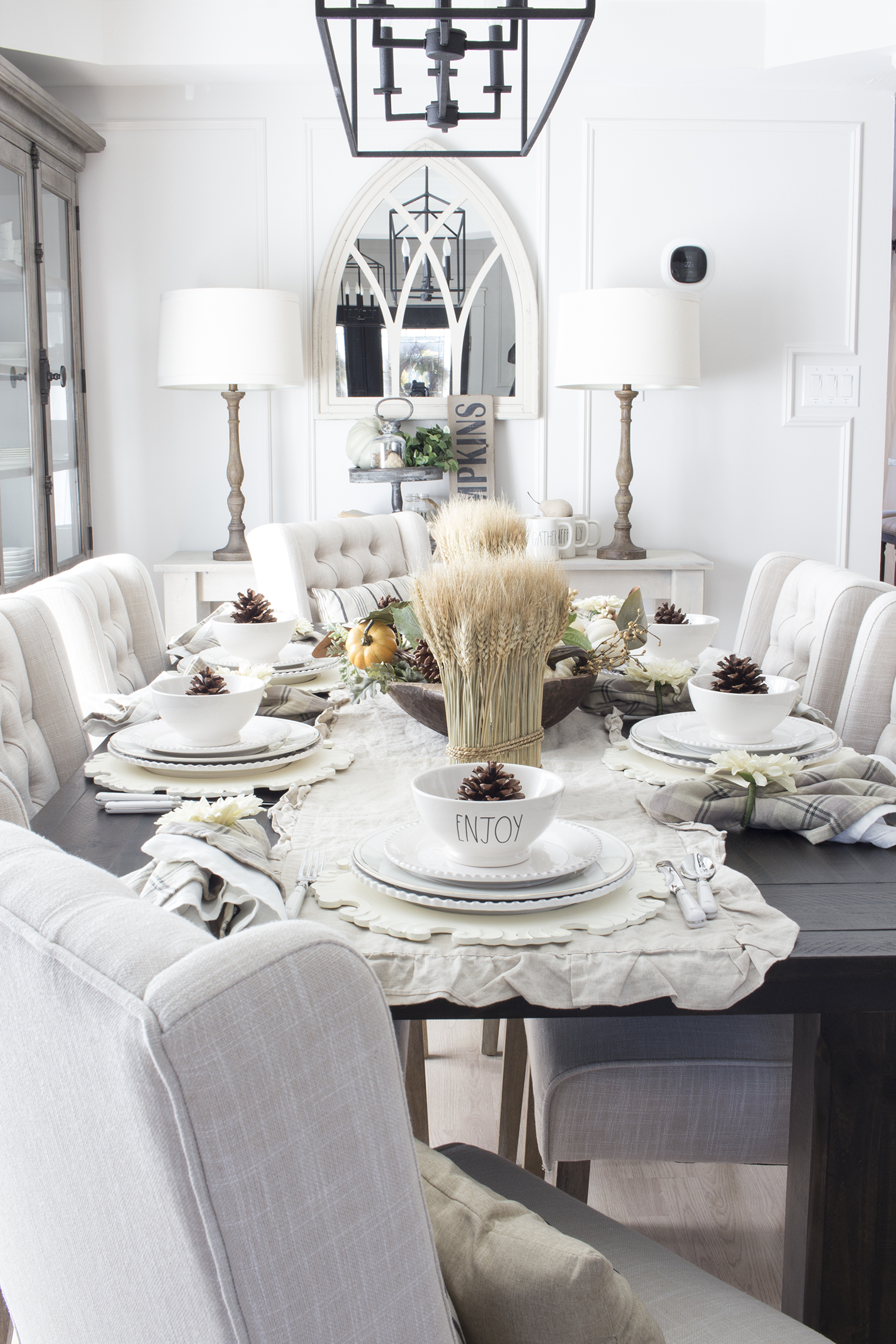 Stalks of wheat and pine cones in dishes on this table setting.