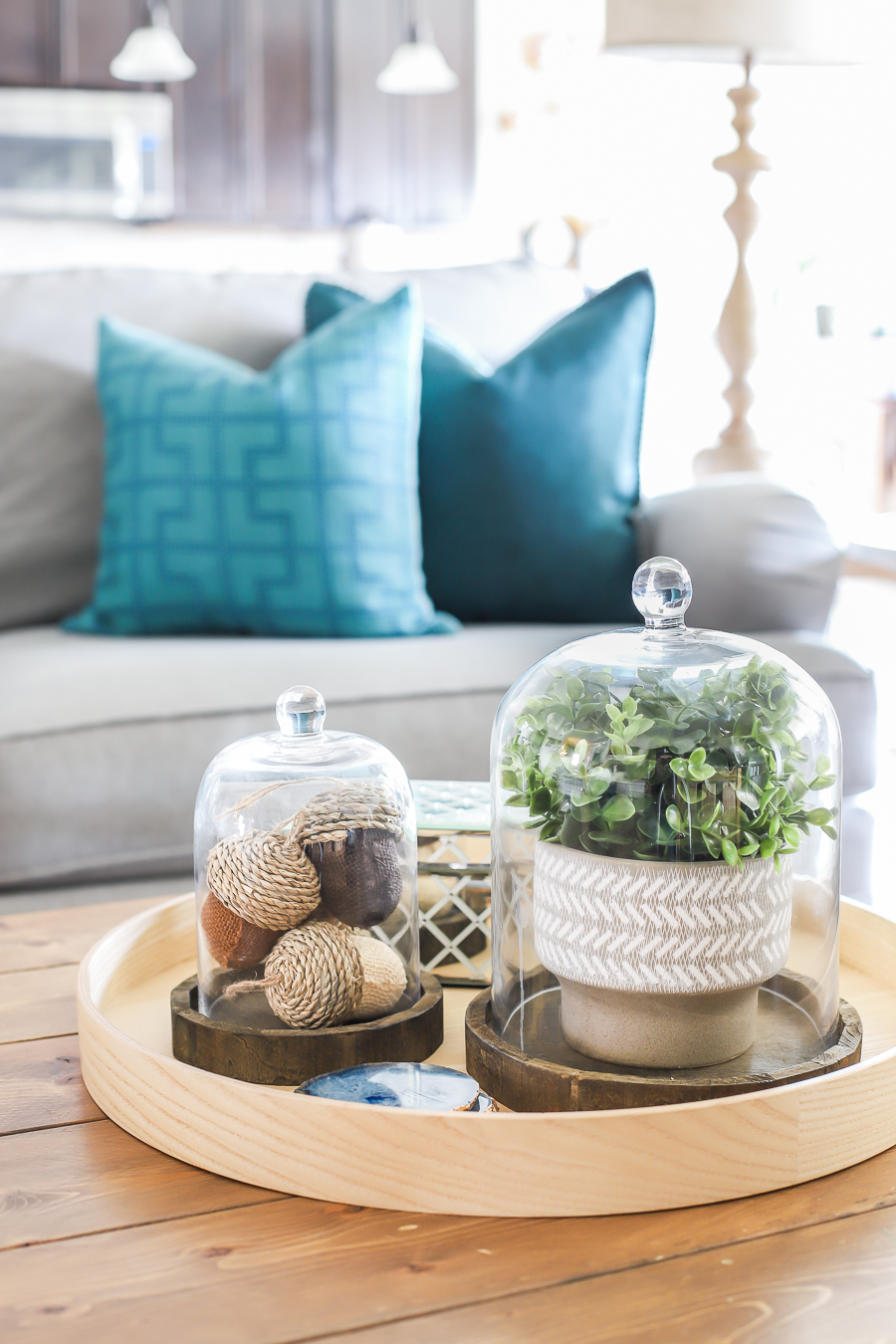 A wooden coffee table with a small tray and cloches on top filled with fall decor.