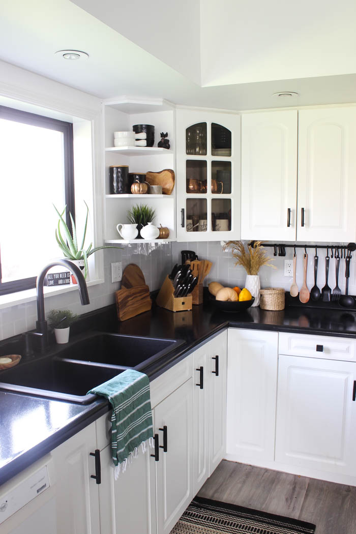 A white and black kitchen with a small rug in front of the sink.