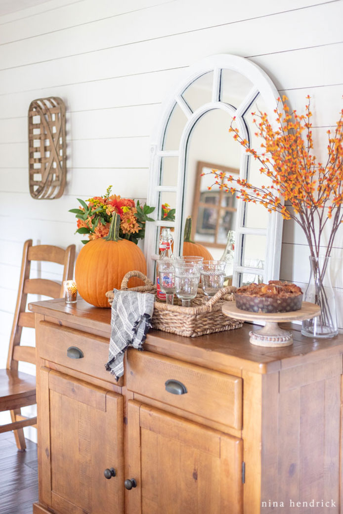 Wooden hutch with a pumpkin and fall branches on top of it.