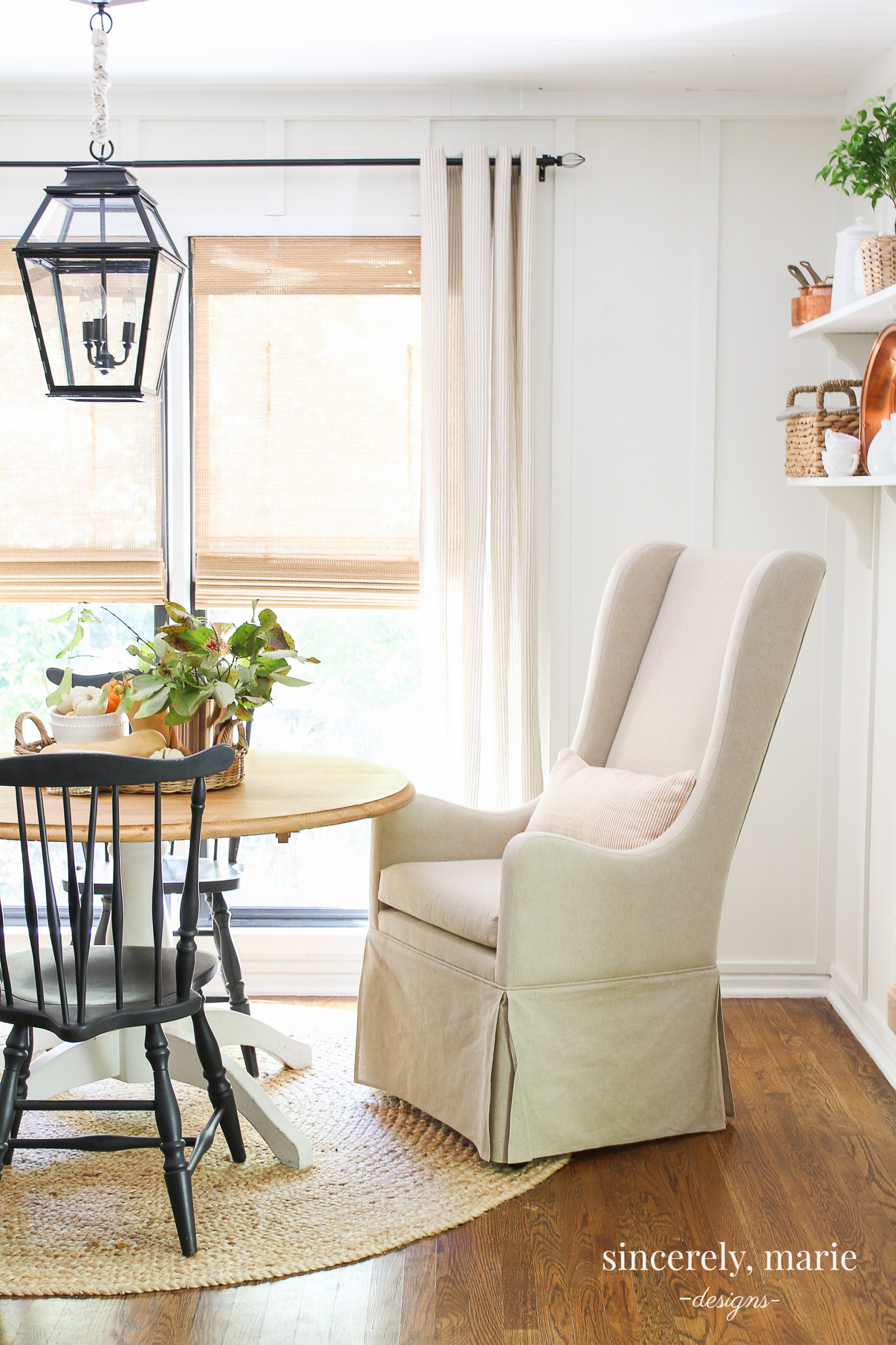 There is a white armchair at a dining room table.