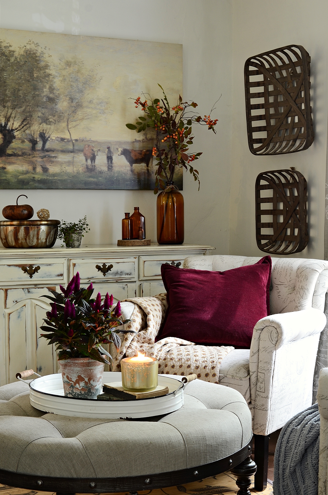 White armchair and ottoman with purple eggplant pillow and small plant.