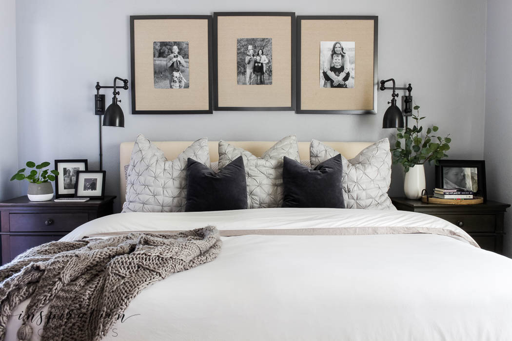 Primary bedroom with black and white pictures above the bed and a small throw blanket on the bed.