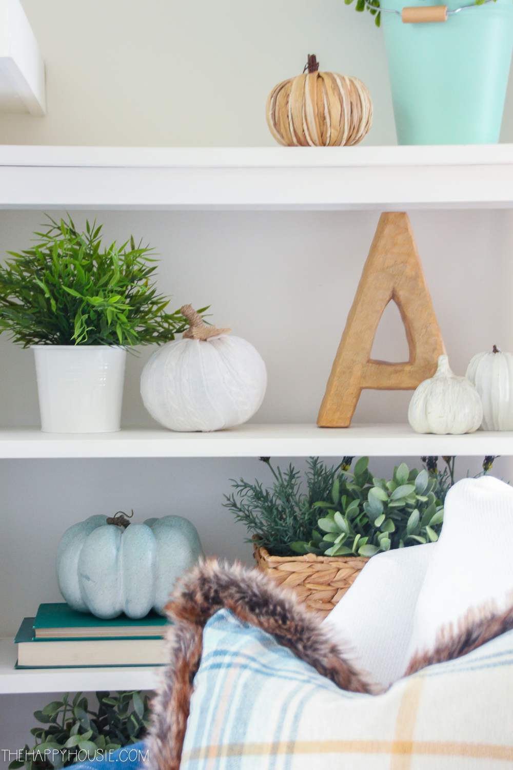 Small white pumpkins are on the shelf behind the chair.