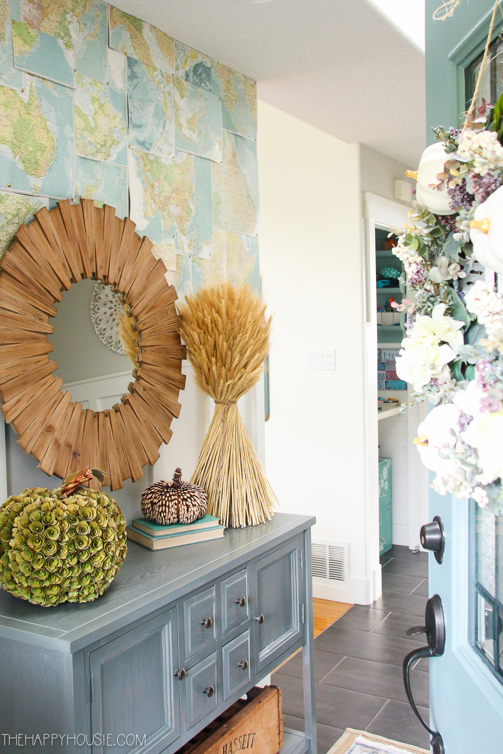 The front door with the fall wreath opened slightly to reveal the inside of the house.