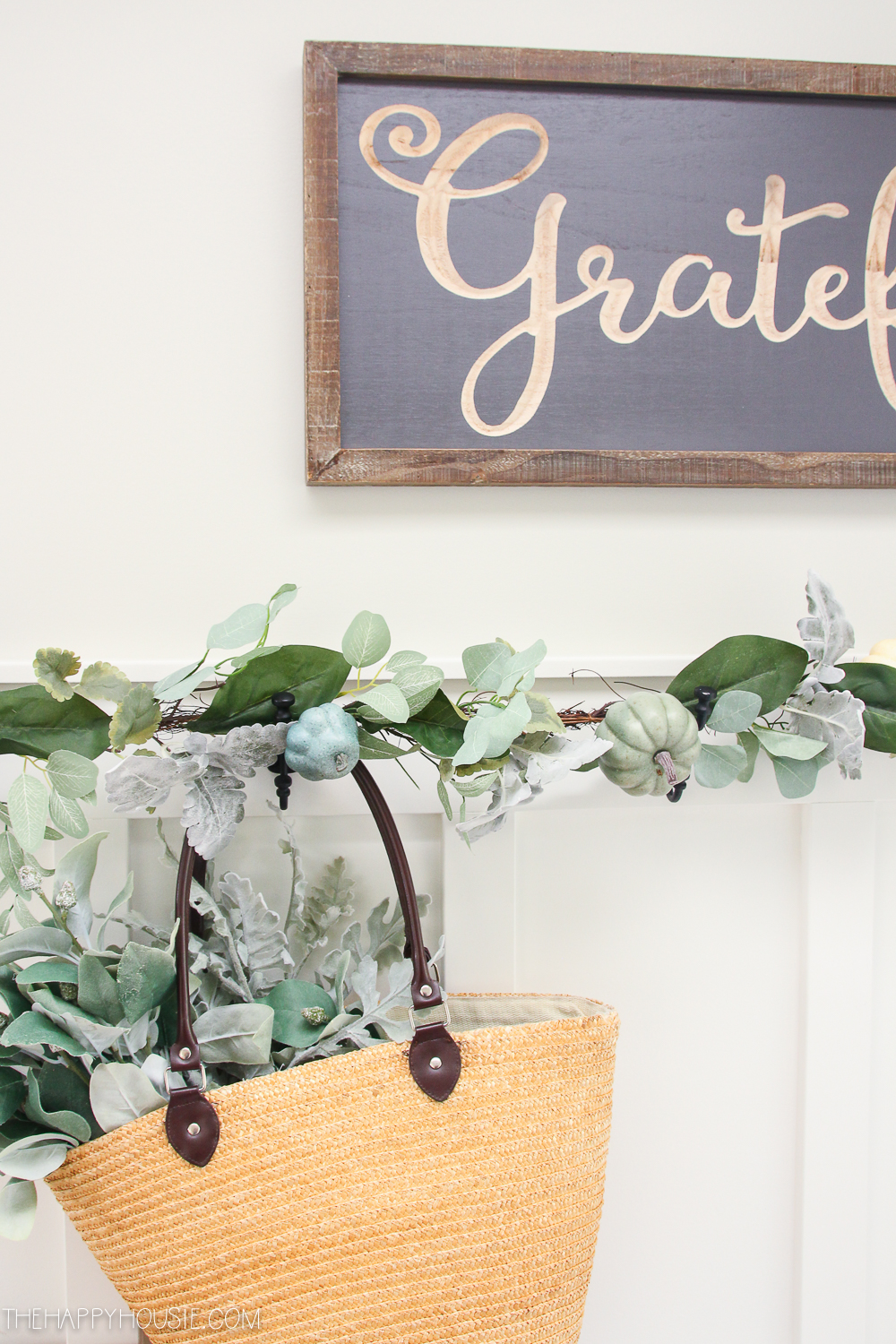 Leaves, and pumpkins on the chair rail with a small bag hanging from it.