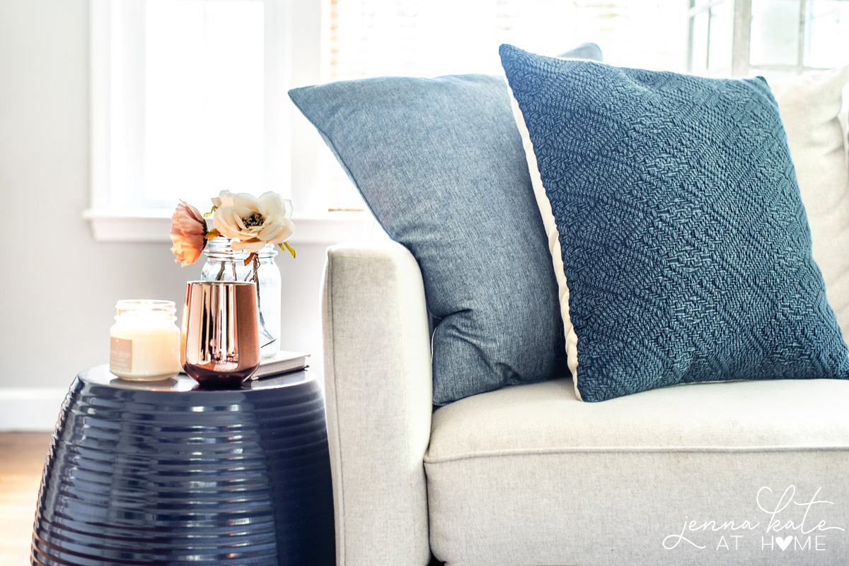 Shades of blue/grey pillows on a neutral couch.